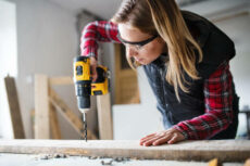 Female carpenter using drill.